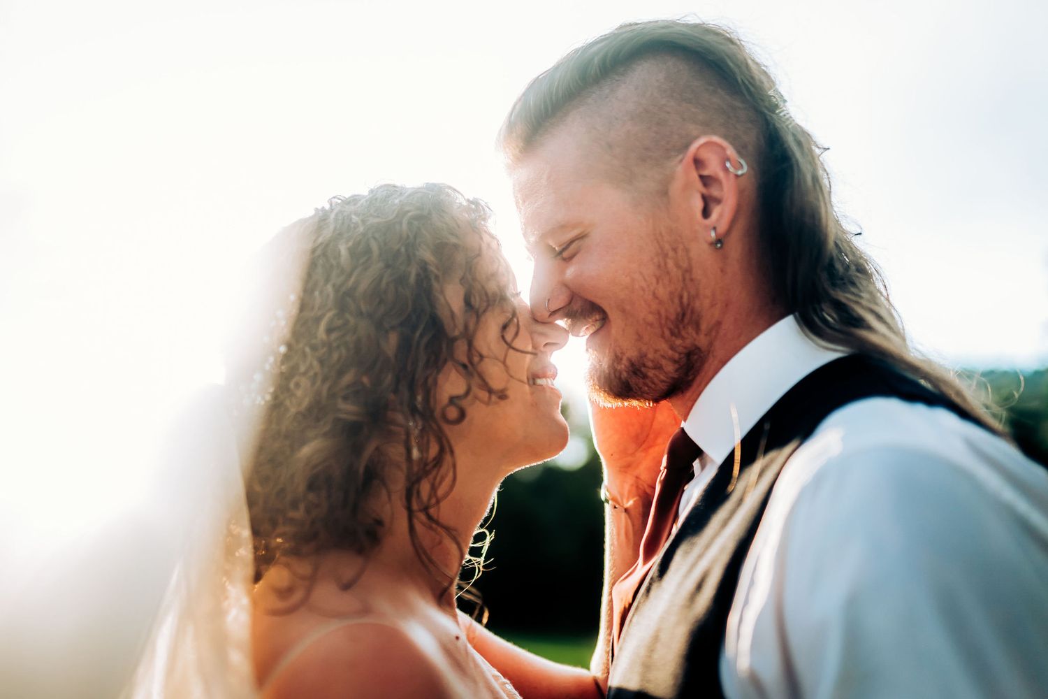 Close up of newlyweds sharing tender moment in golden sunlight.