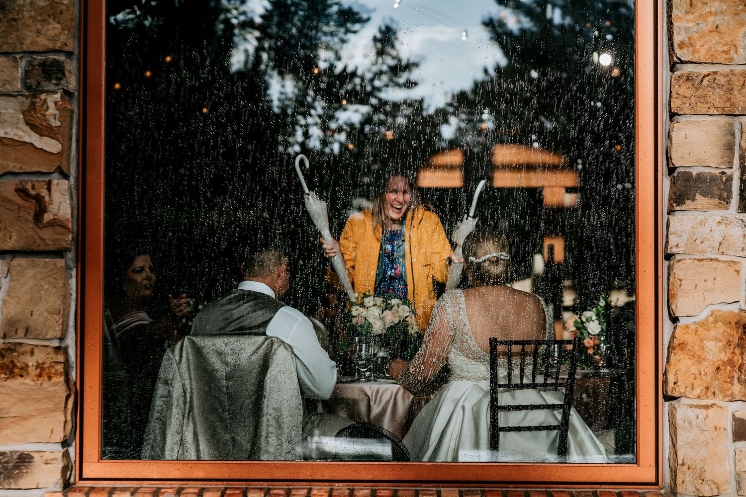 View through window of wedding reception with stone walls and warm lighting.