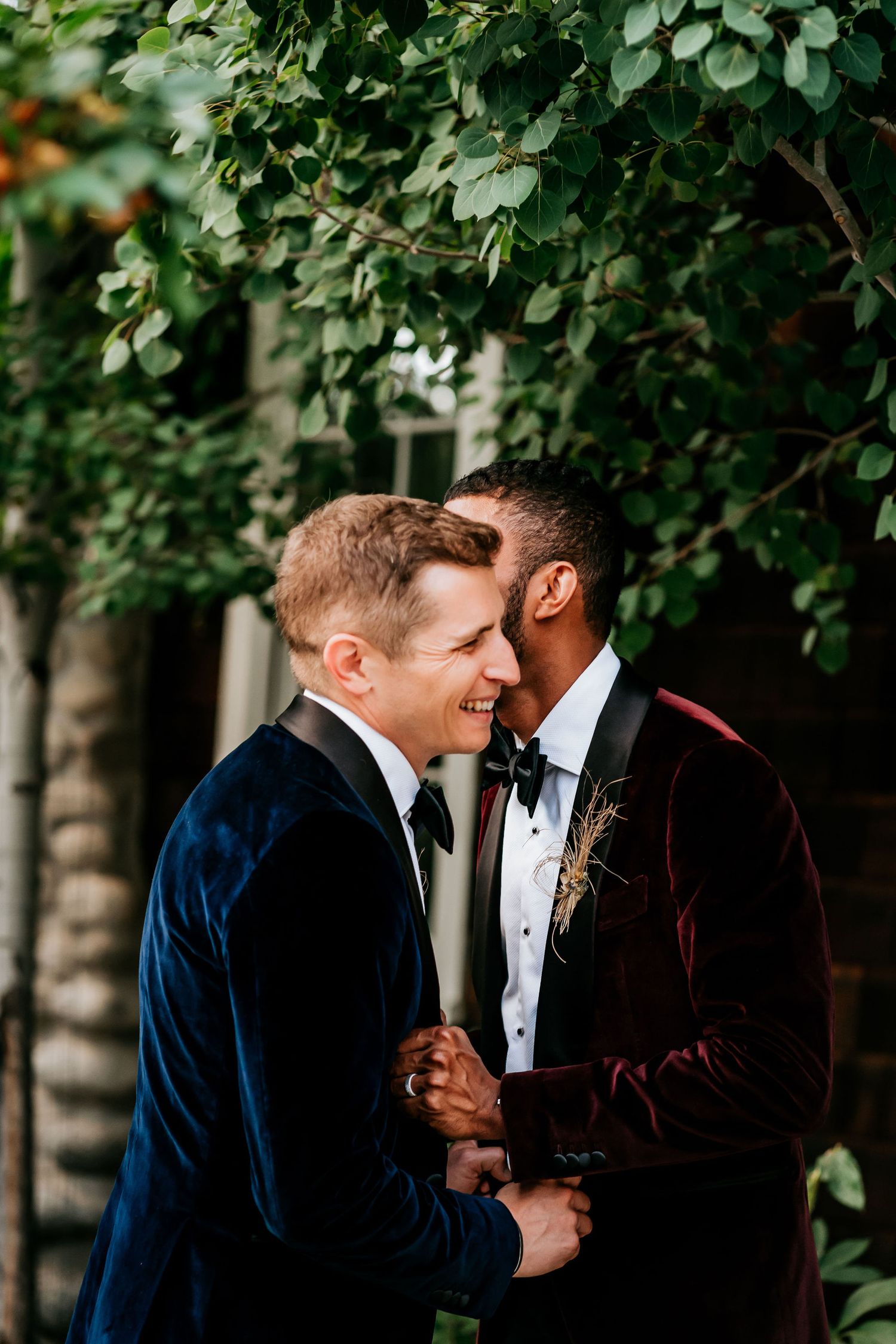Intimate moment between newlyweds surrounded by lush green foliage.