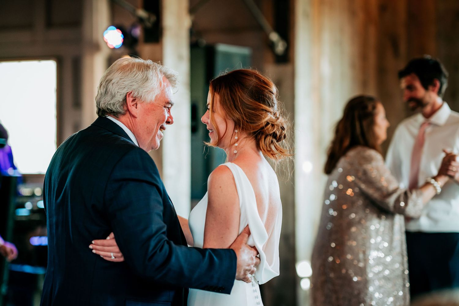 Couples dancing together during an intimate wedding reception under warm lighting.