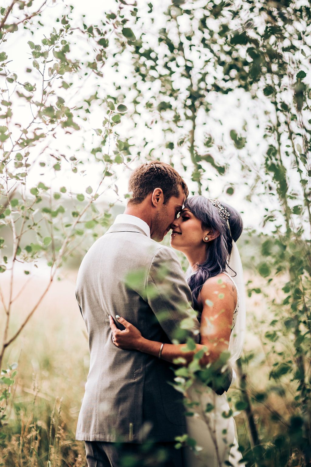 Intimate wedding moment captured in dreamy outdoor setting with soft bokeh effect.
