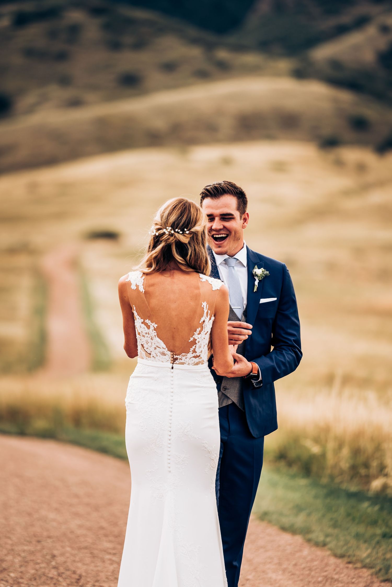 Intimate wedding moment shared on mountain path with rolling hills in background.