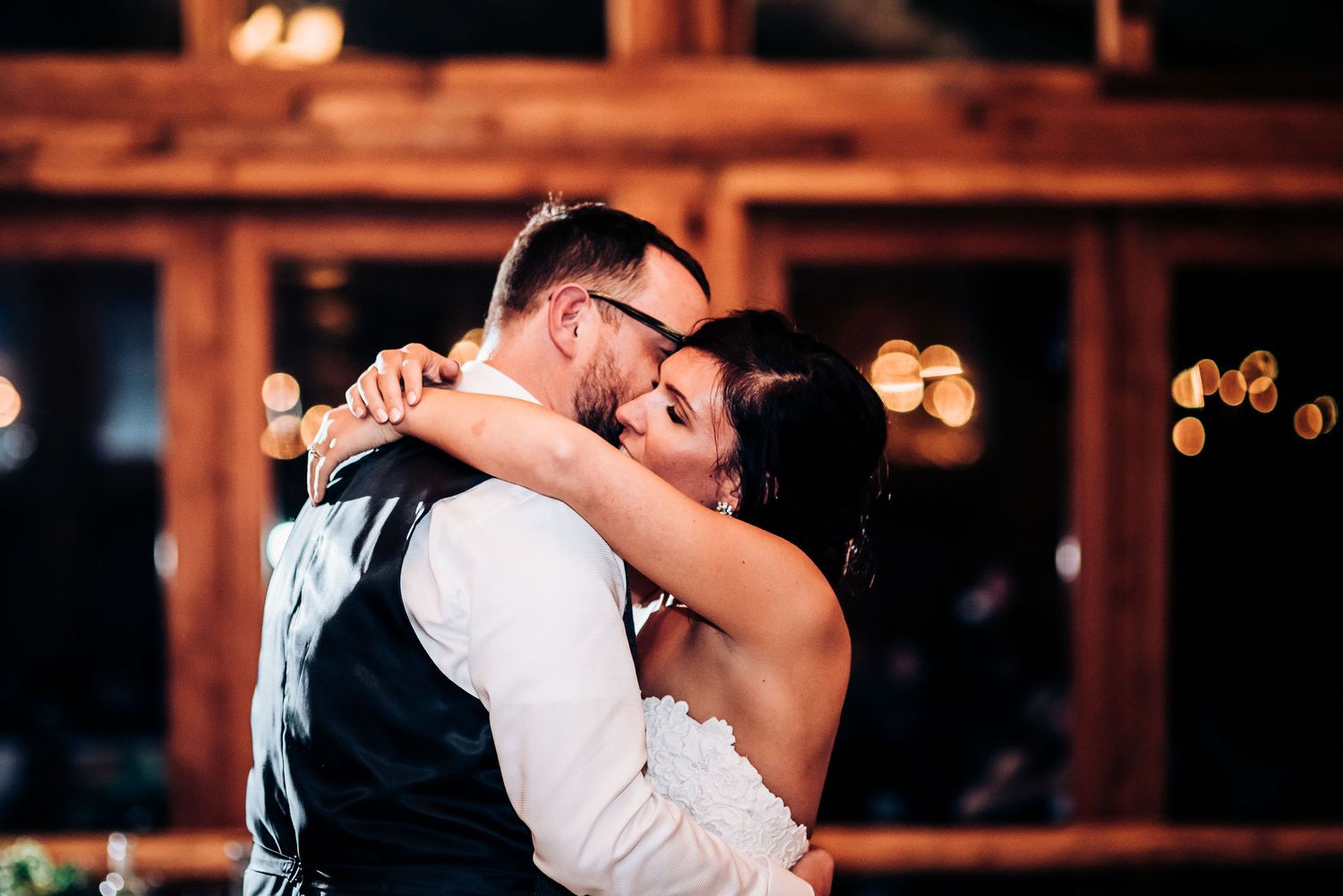 Intimate dance moment captured in a rustic barn venue with twinkling lights.
