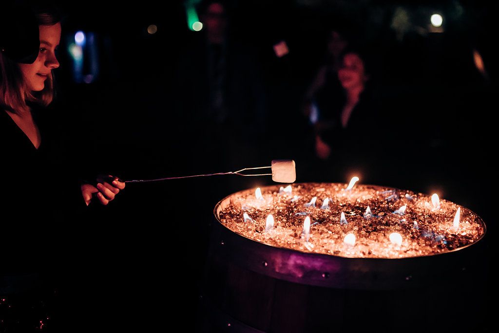 Roasting marshmallows over a fire pit filled with glowing embers in the dark.