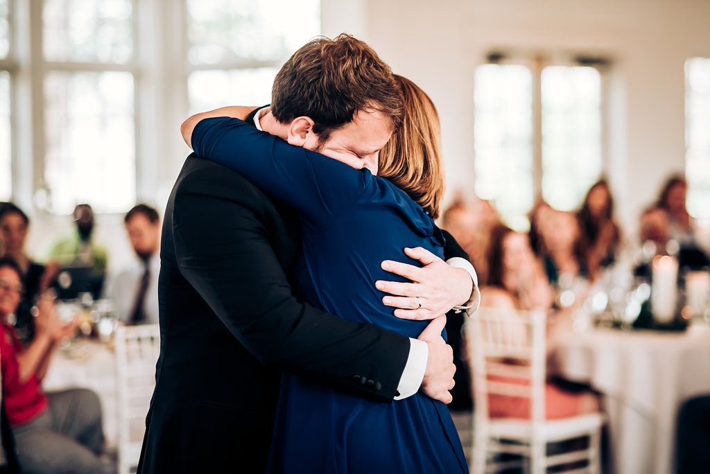 Emotional embrace between two guests during a wedding reception celebration.