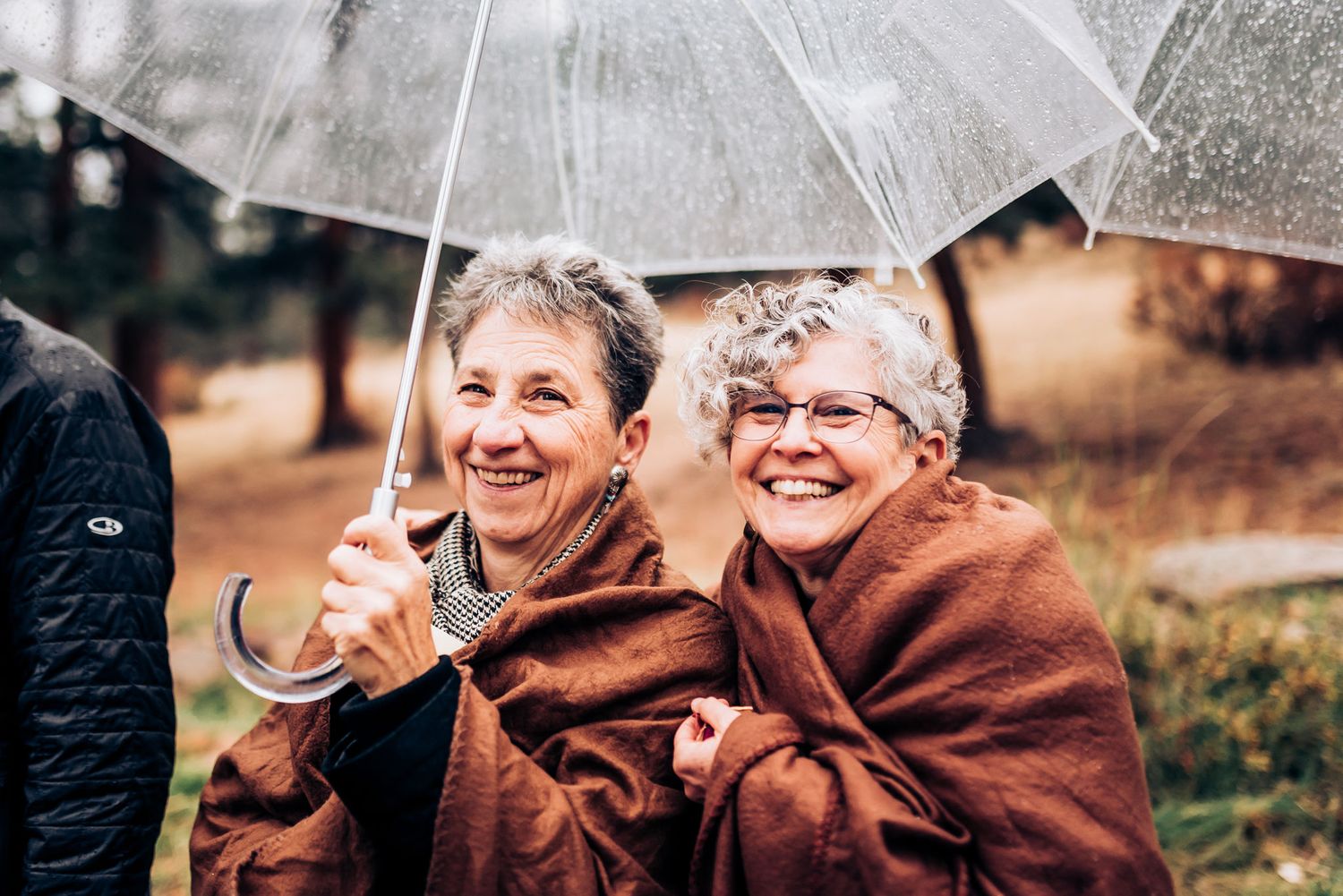 Two people sharing a laugh under a clear umbrella on a rainy day.