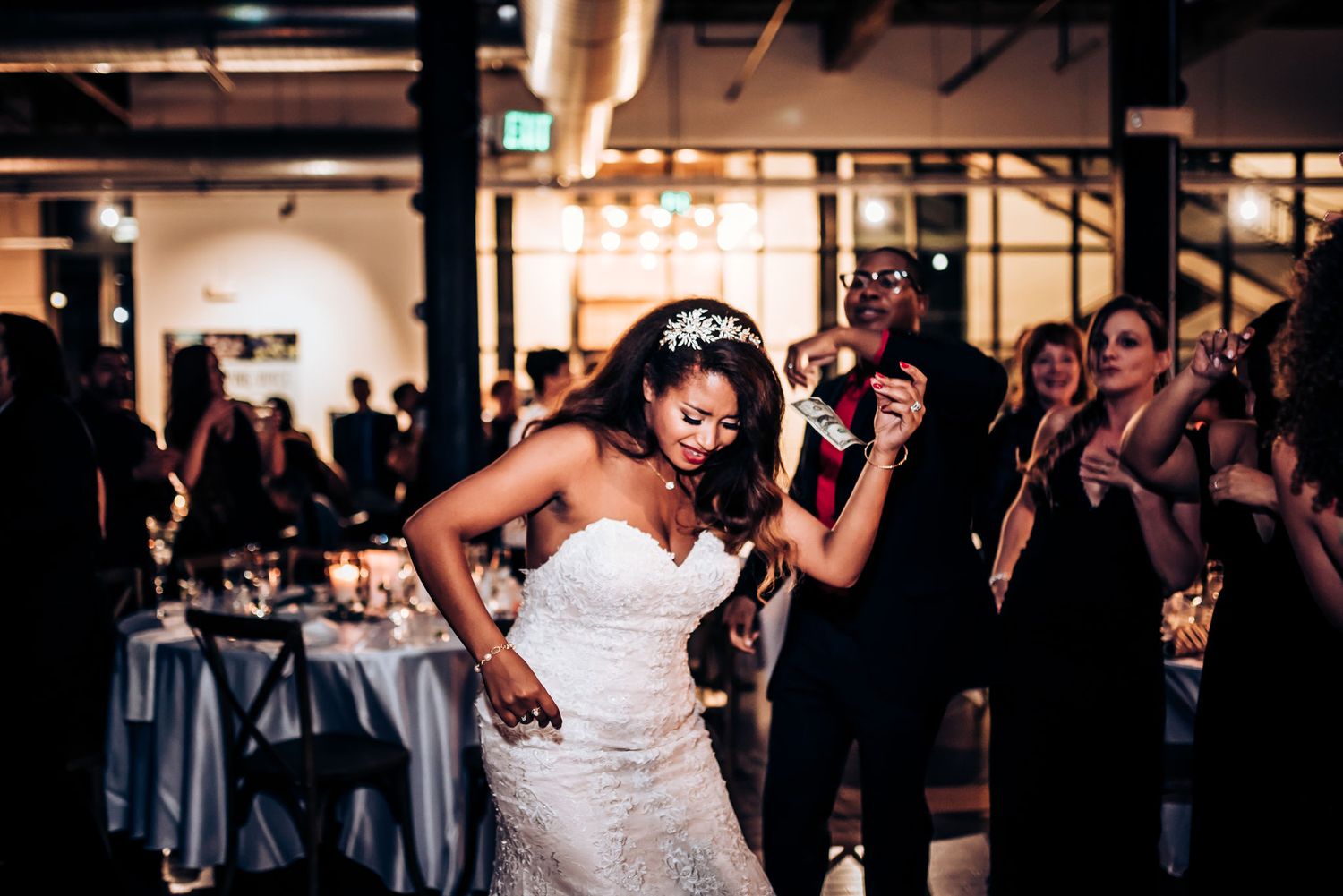 A joyful bride in a white dress dancing and celebrating at her wedding reception.