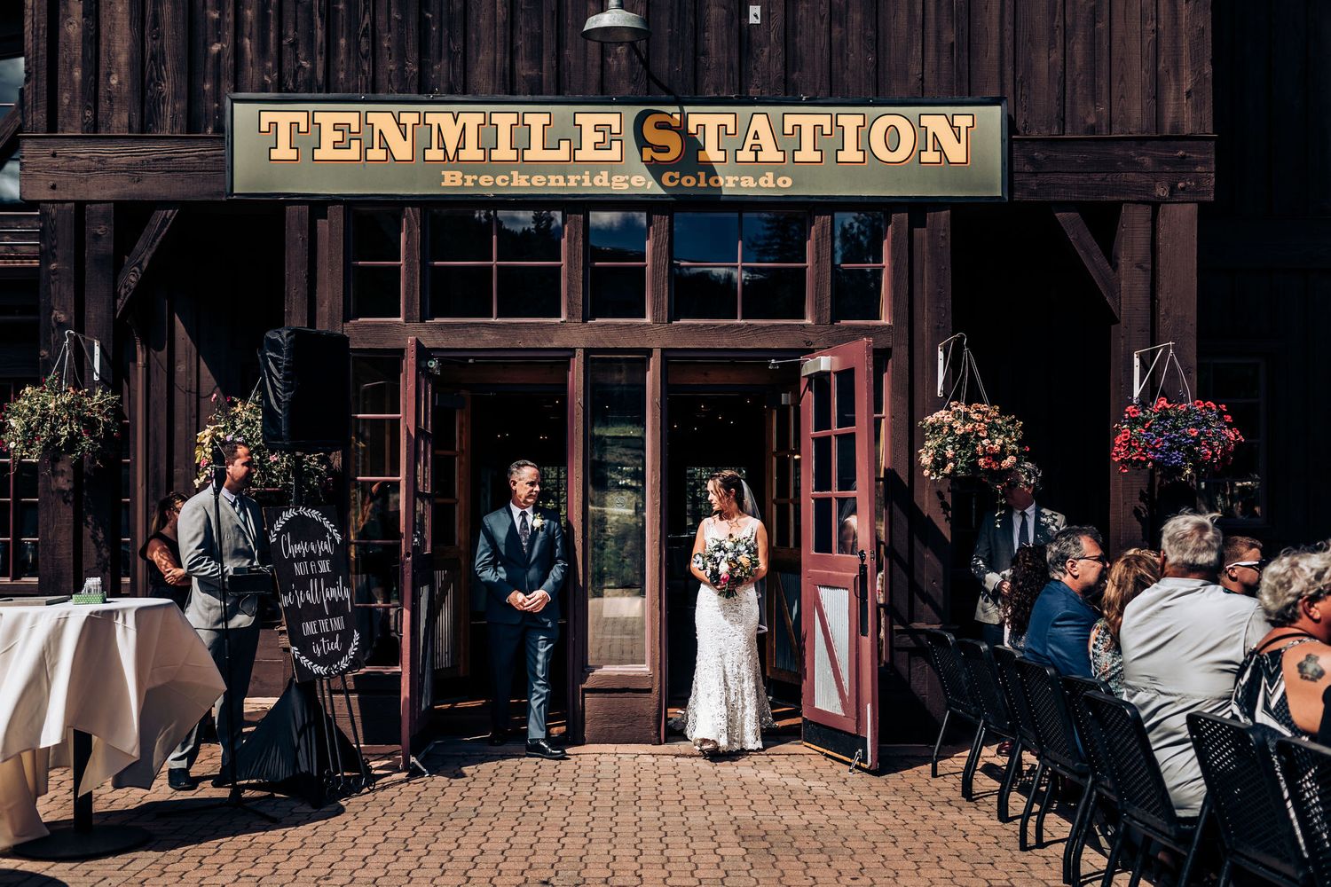 Wedding ceremony outside Ten Mile Station with guests seated on rustic wooden patio.