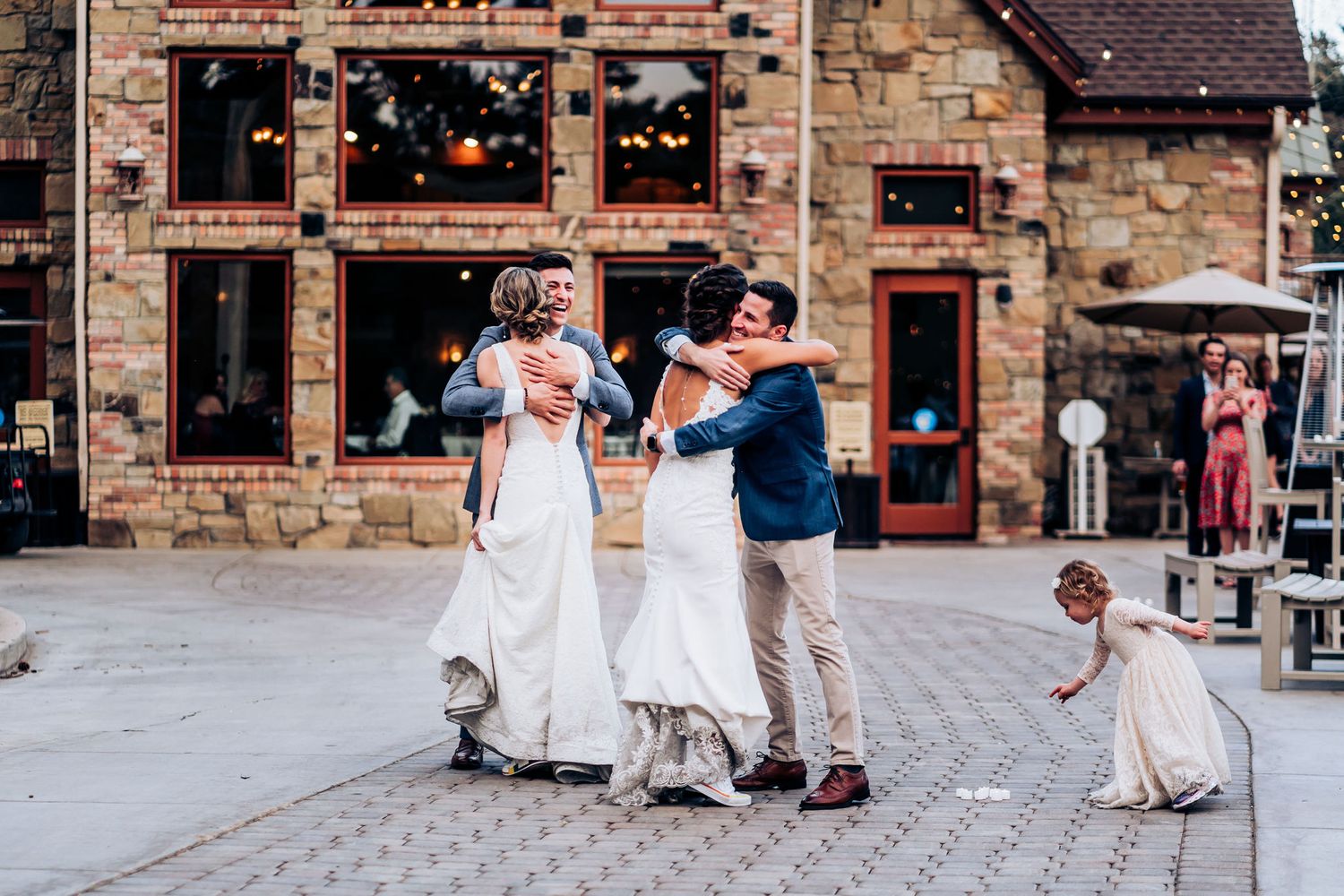 People dance joyfully together on cobblestone street outside rustic stone building with glowing windows.