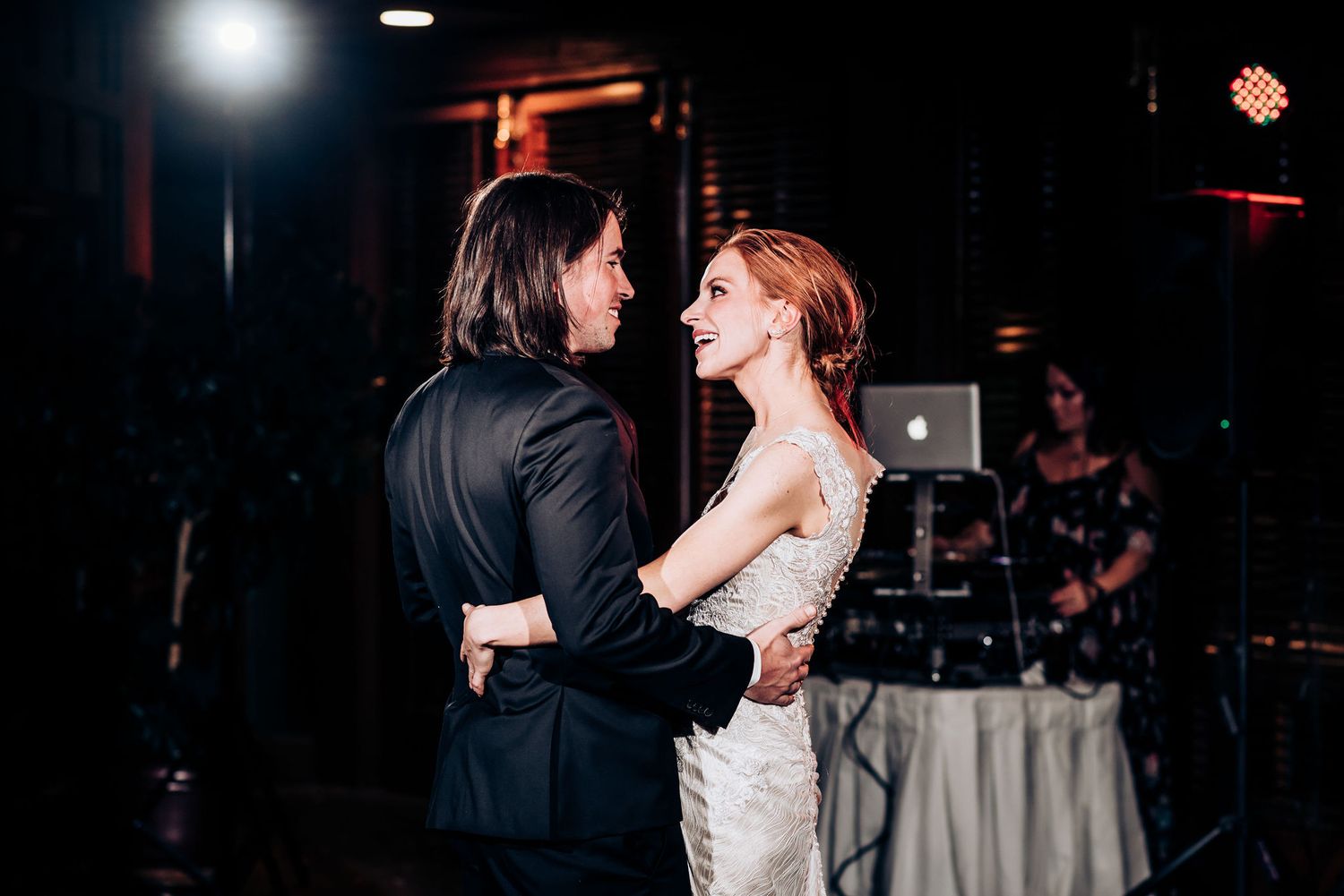 Couple shares romantic first dance at dimly lit wedding reception venue.