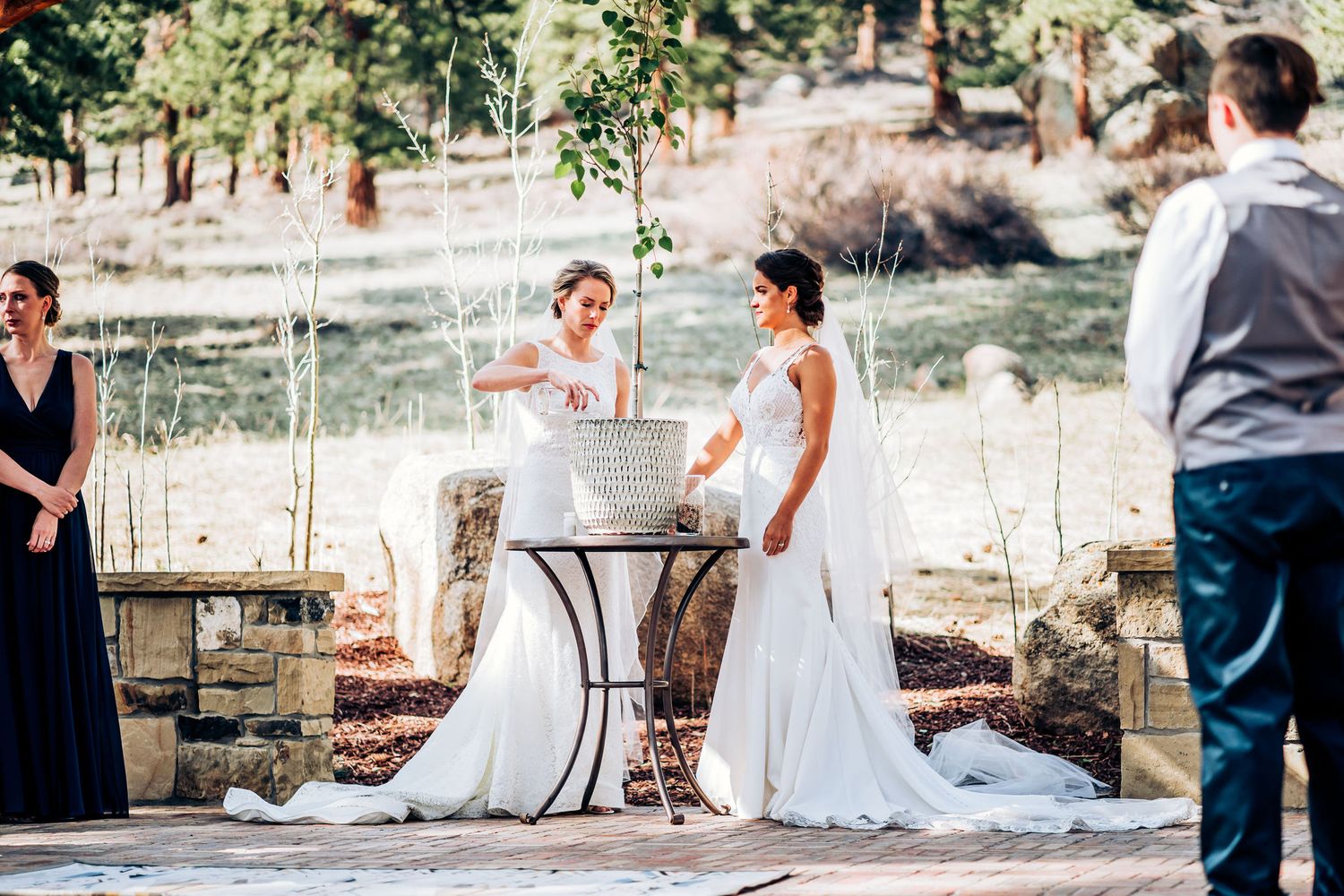 A candid moment during an outdoor wedding ceremony with attendants watching from the sides.