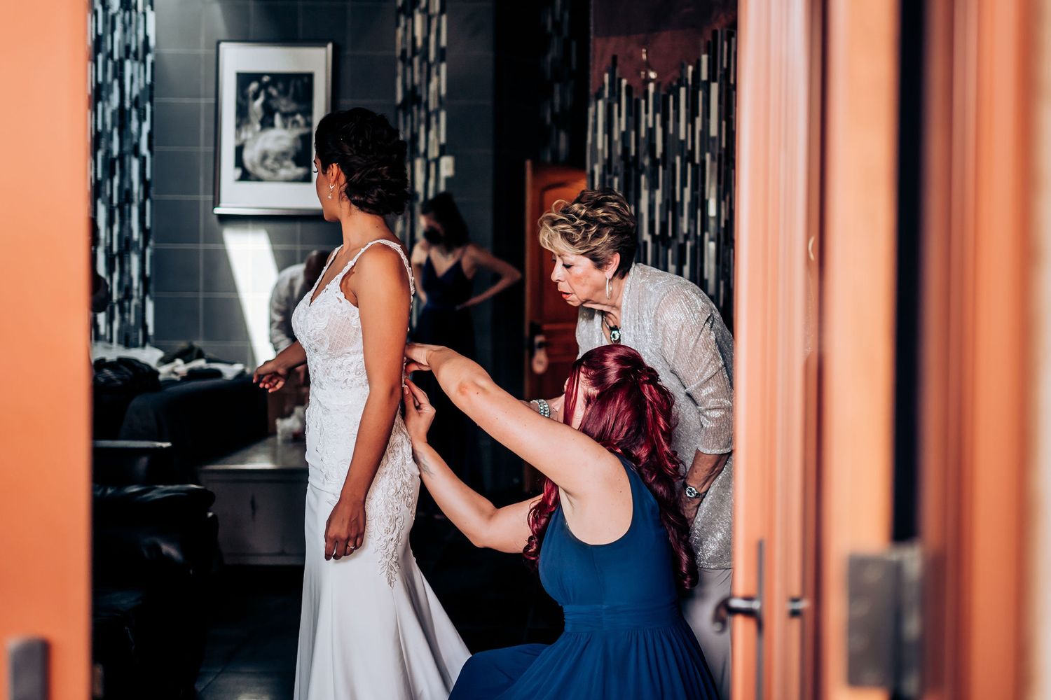 Wedding dress preparations with multiple helpers making final adjustments.