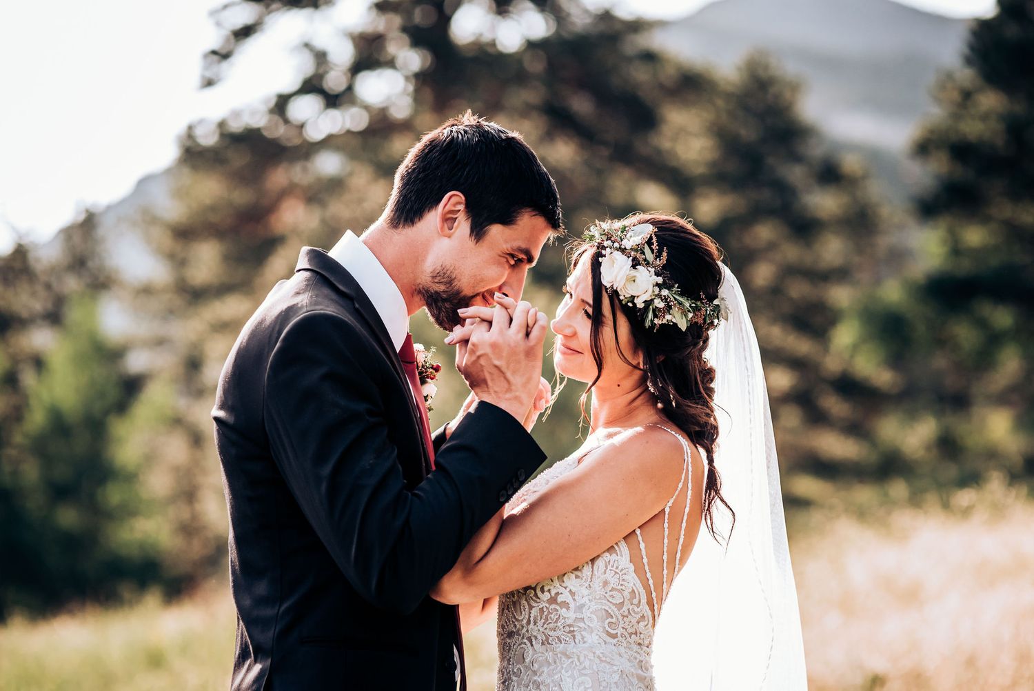 Intimate wedding moment captured in mountain setting with couple in formal attire and floral details.