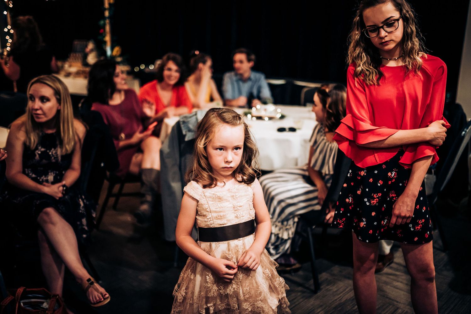 Wedding reception guests watching entertainment in dimly lit venue.