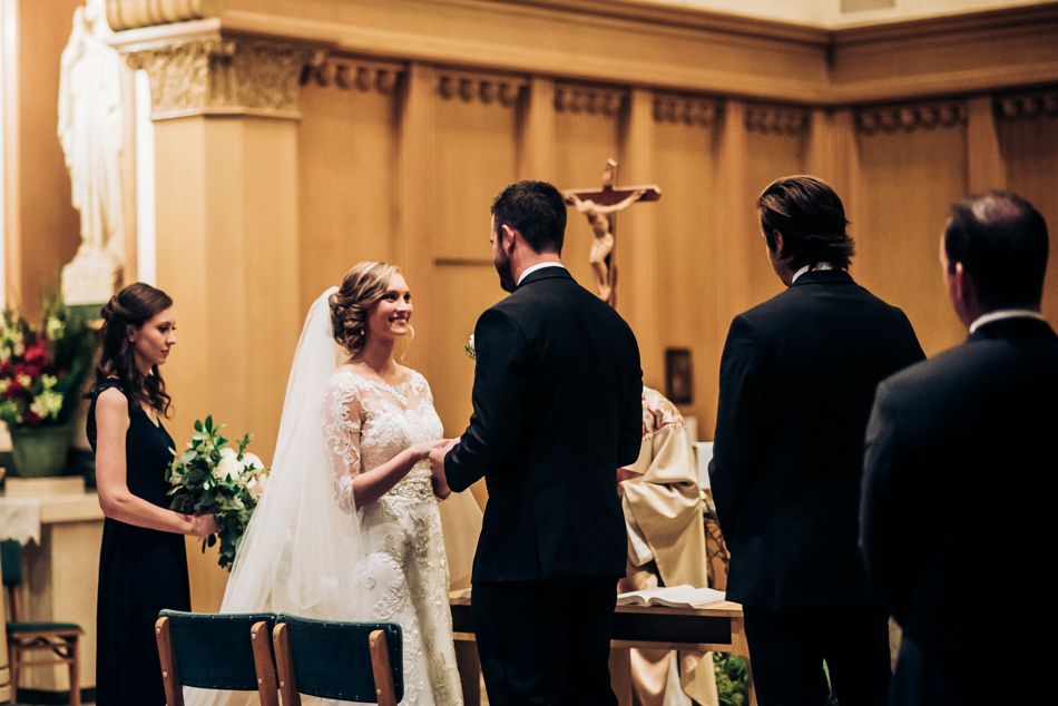 A traditional church wedding ceremony taking place at an altar with ornate columns and floral arrangements.