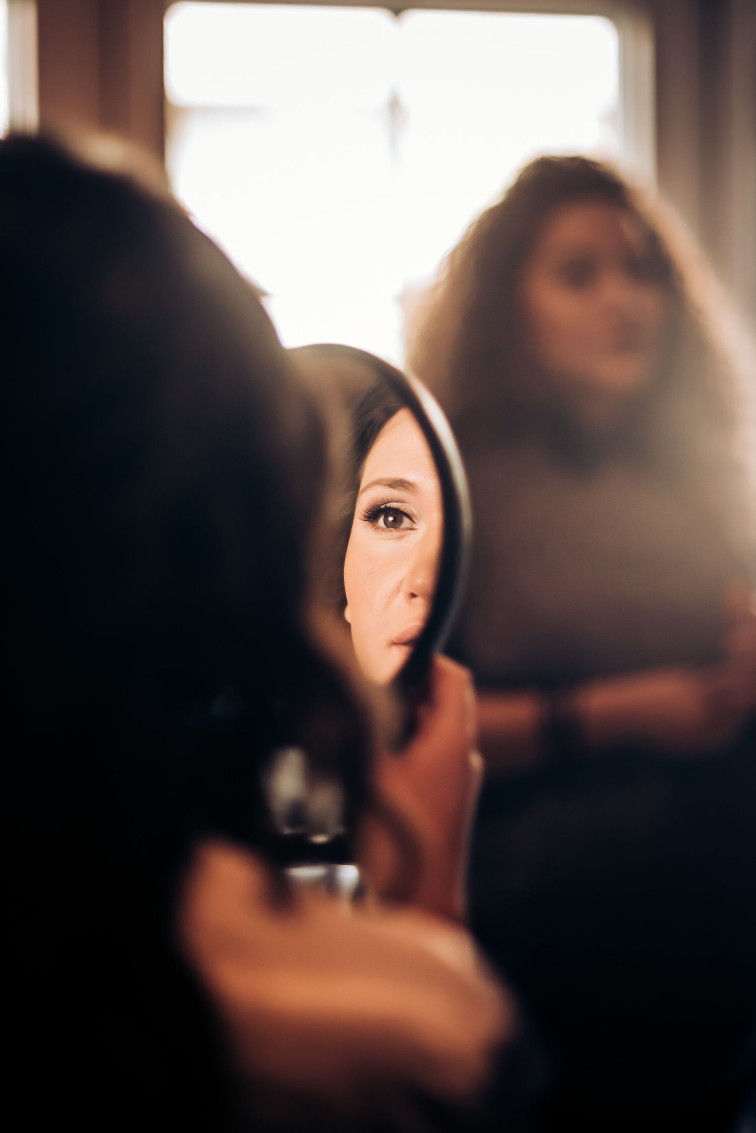 Artistic reflection shot of makeup preparation in a handheld mirror.