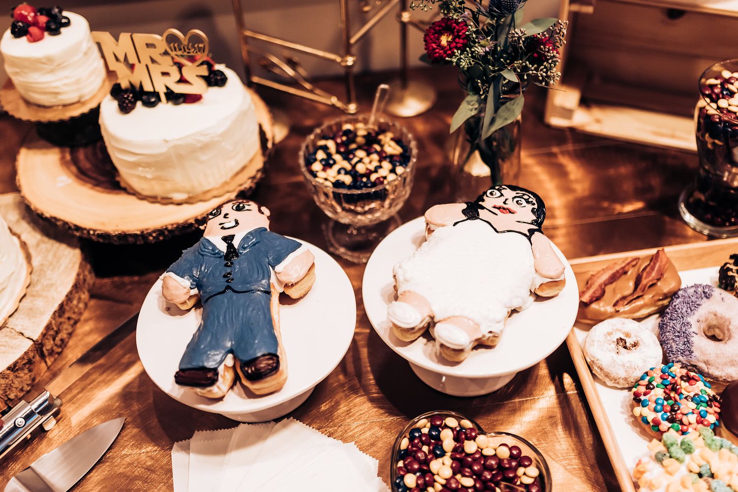 Wedding dessert display featuring decorated cookies and treats on rustic wood slices.