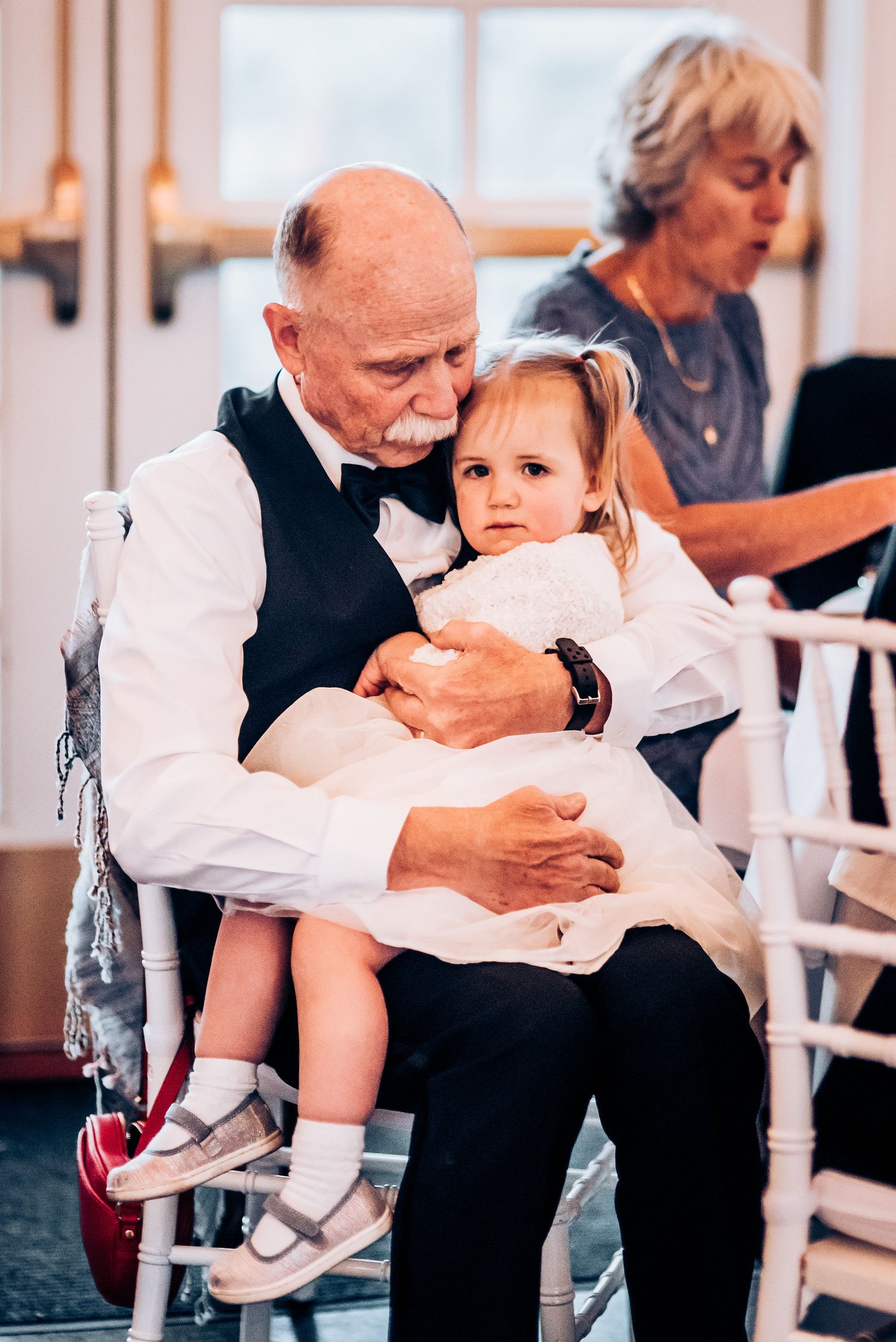 Tender moment captured during a formal event with white chiavari chairs.