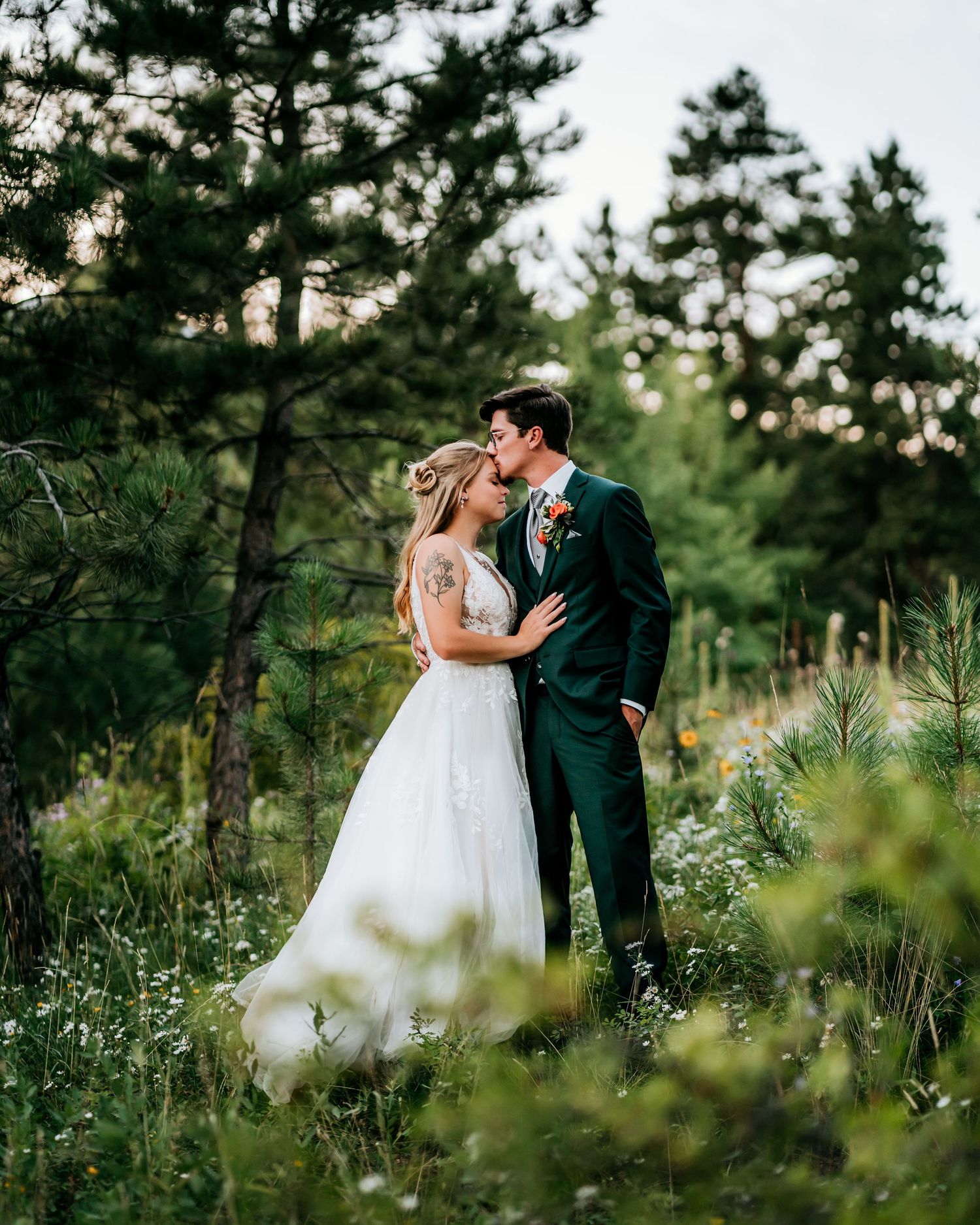 Romantic wedding portraits in a natural pine forest setting with flowing white gown.