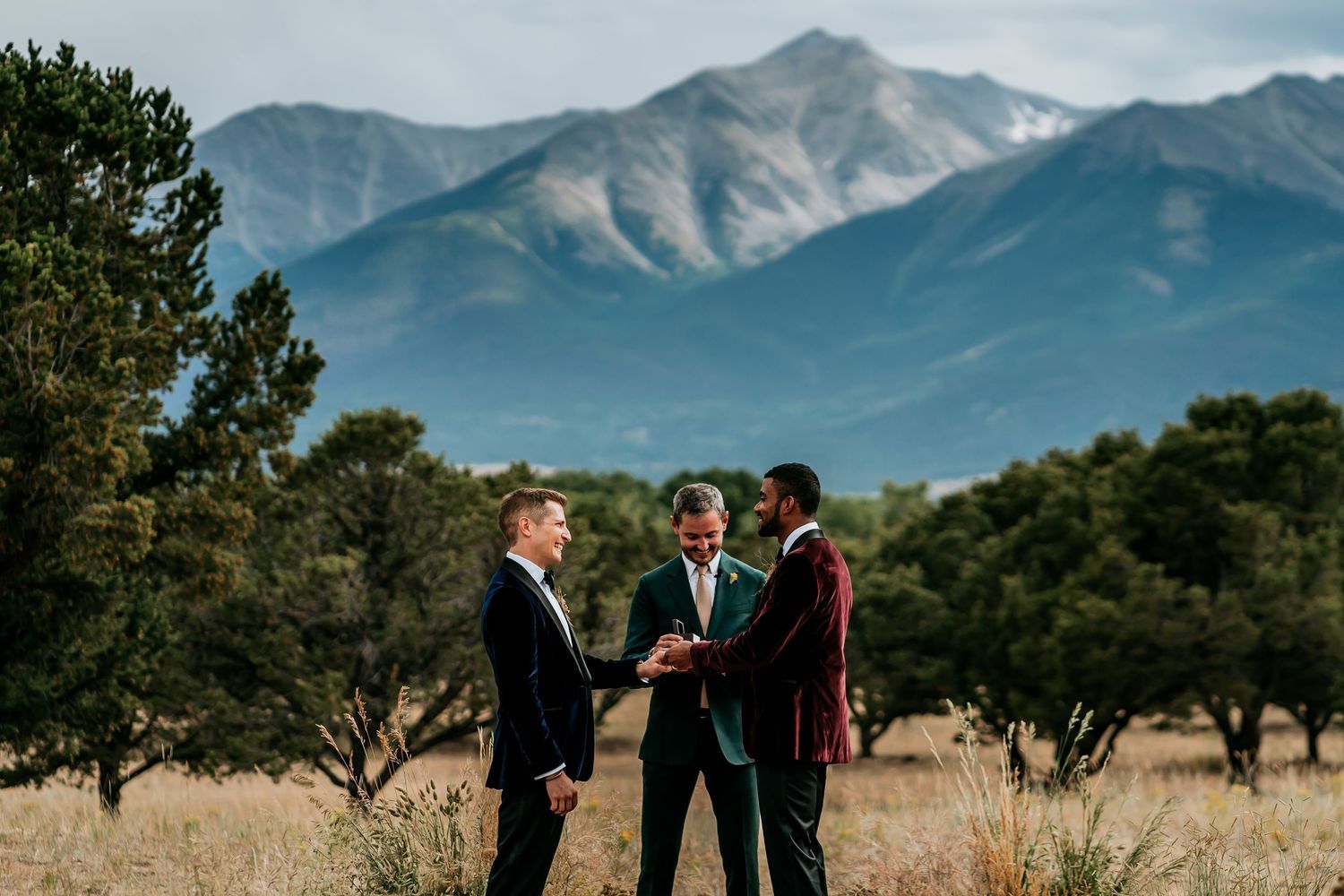 Wedding party gathering in scenic mountain landscape under blue skies.