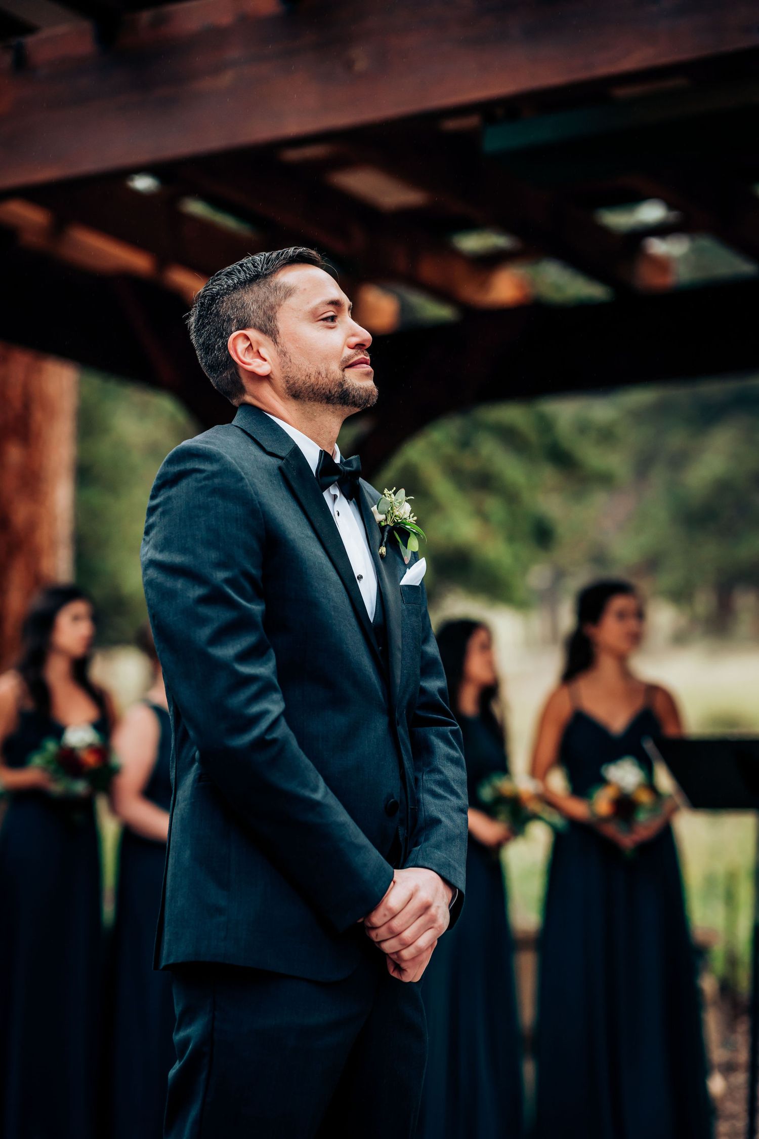 An emotional moment during an outdoor wedding ceremony with bridesmaids wearing dark blue dresses.