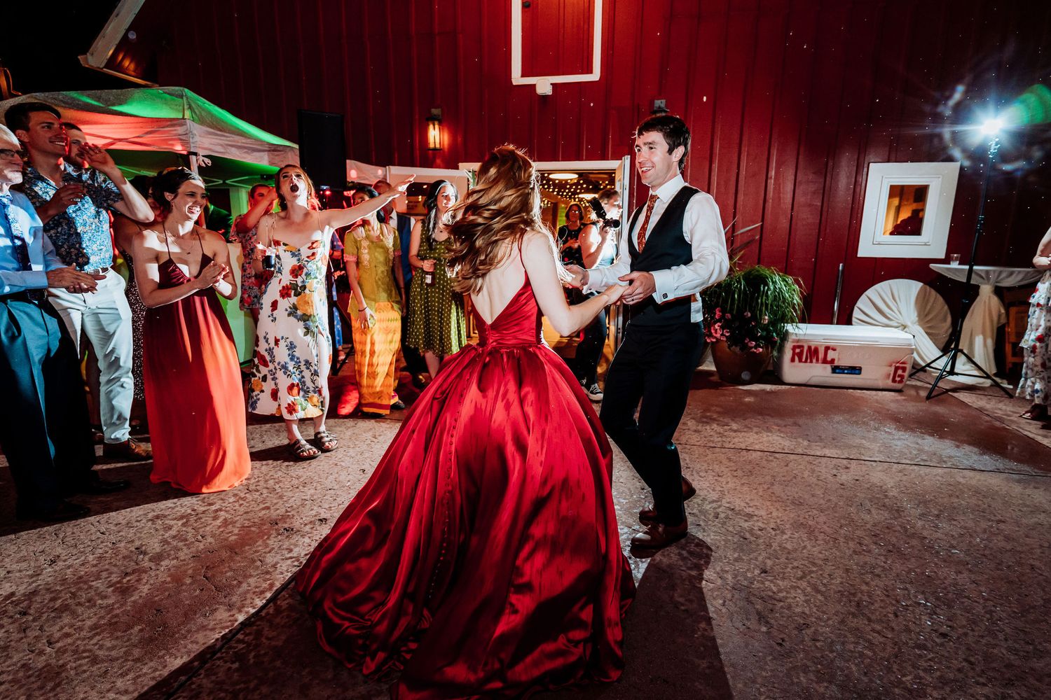 Couple dancing at a wedding reception with the bride wearing a dramatic red ball gown.