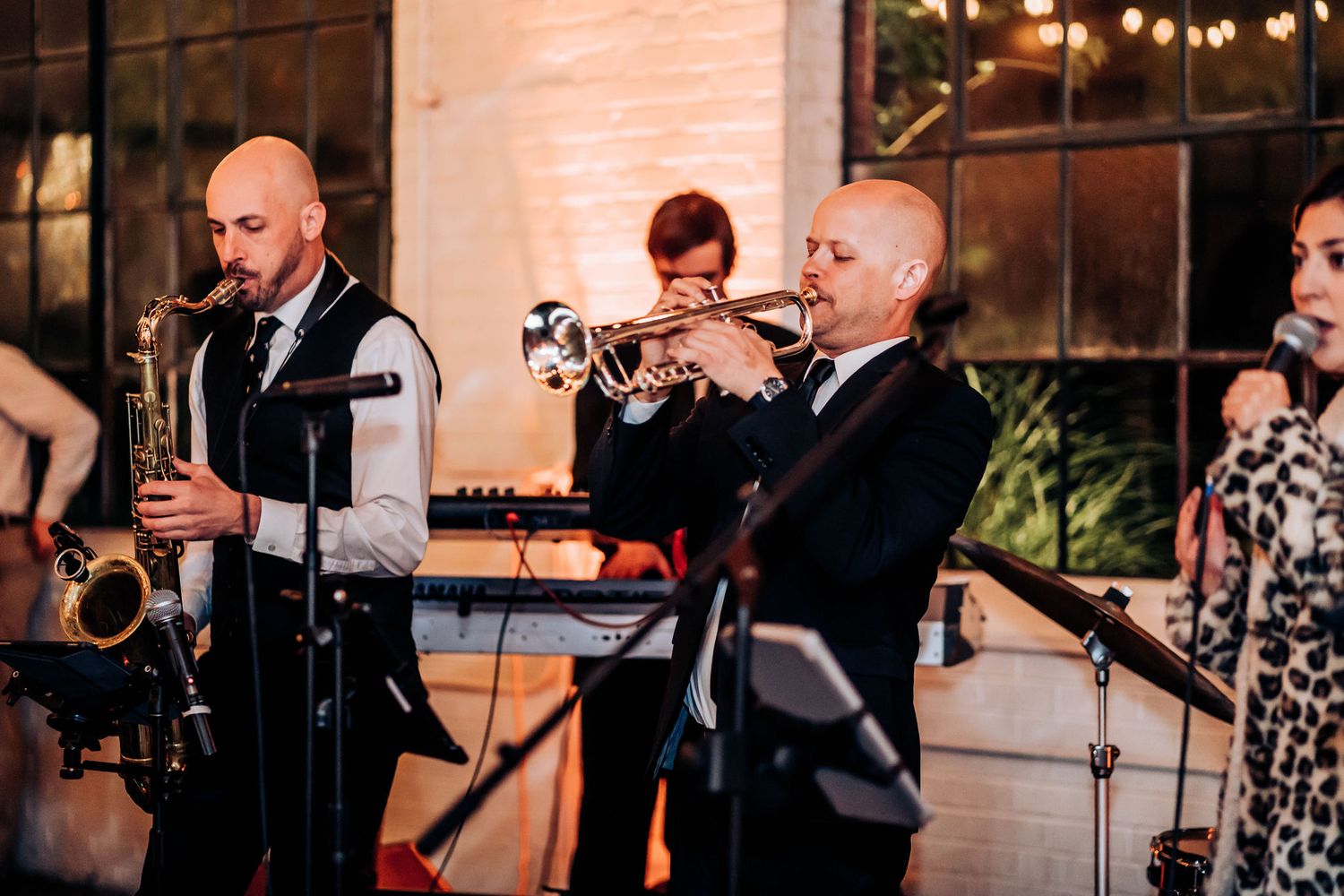 Live wedding band performs with trumpet and saxophone players in formal attire.
