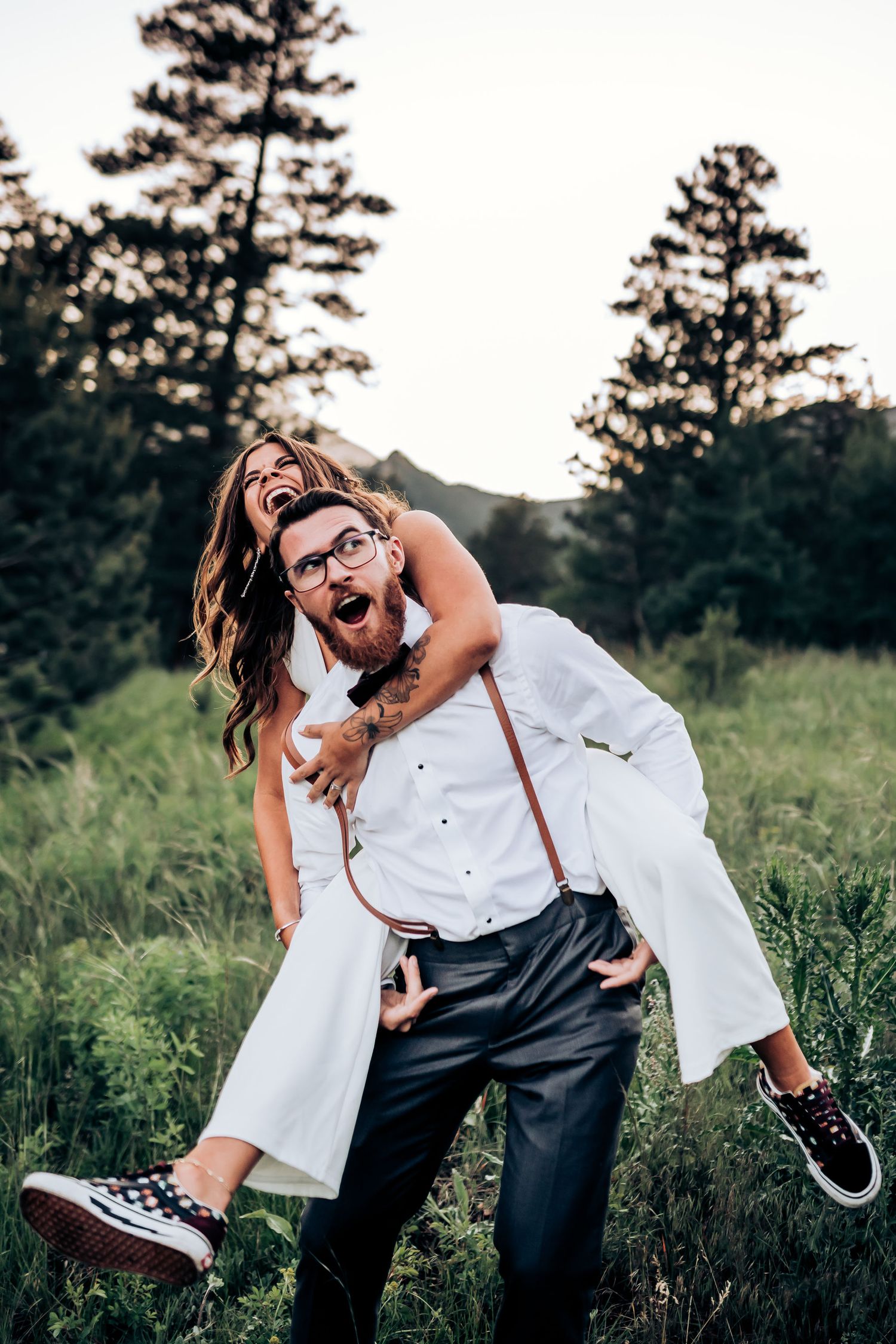 Playful piggyback ride moment captured against a mountainous backdrop with pine trees.