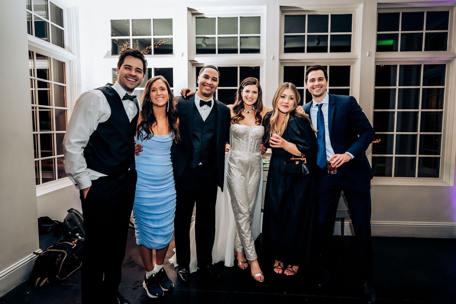 Wedding party members pose together in formal attire for evening celebration photo.