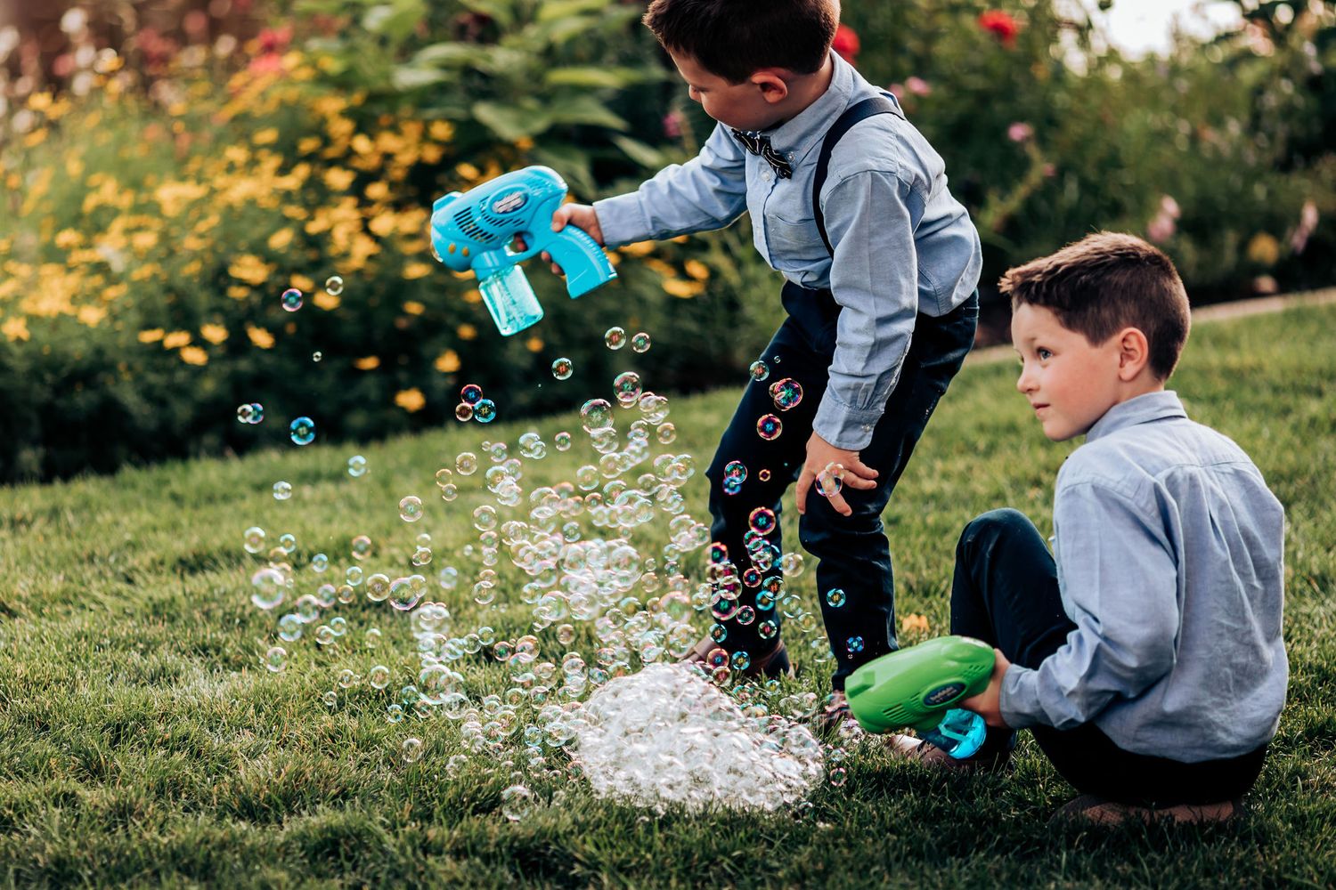 Two children play with bubble wands in a garden, creating streams of bubbles in the air.