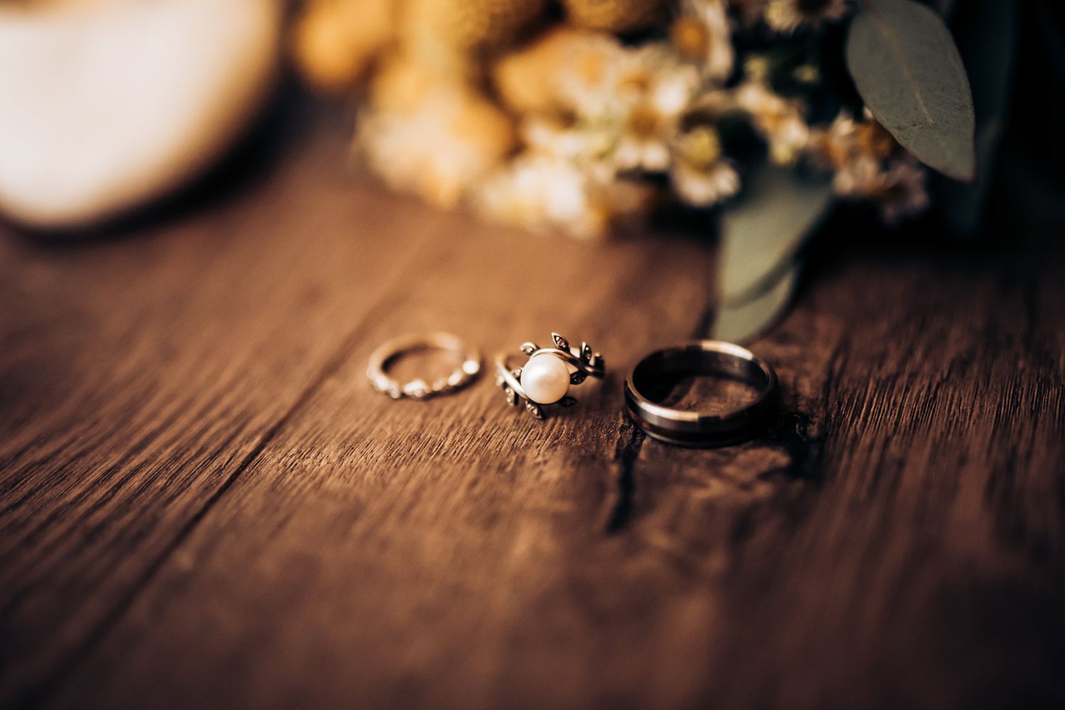 Wedding rings displayed on rustic wooden surface with soft lighting.