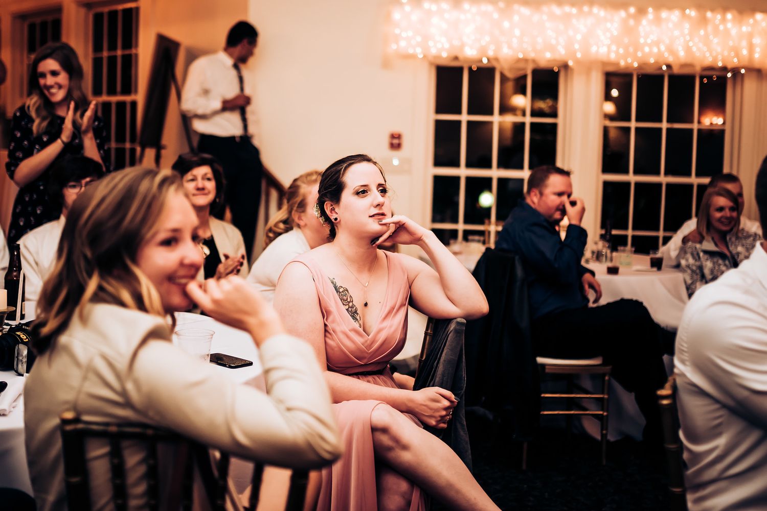 Wedding reception guests share laughter and conversation during evening celebration.