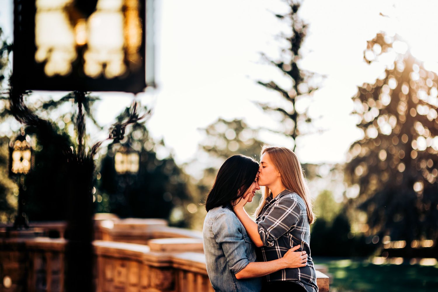Tender embrace captured against sunset with ornate lamp post in foreground.