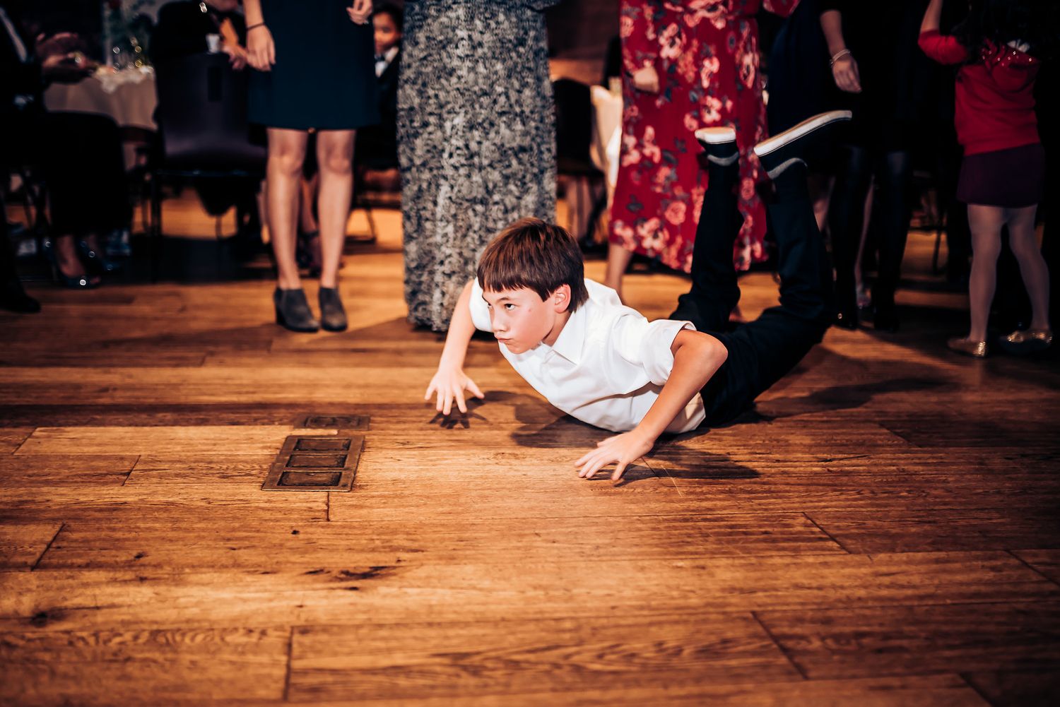 Guest performing breakdance moves on wooden floor during reception party.