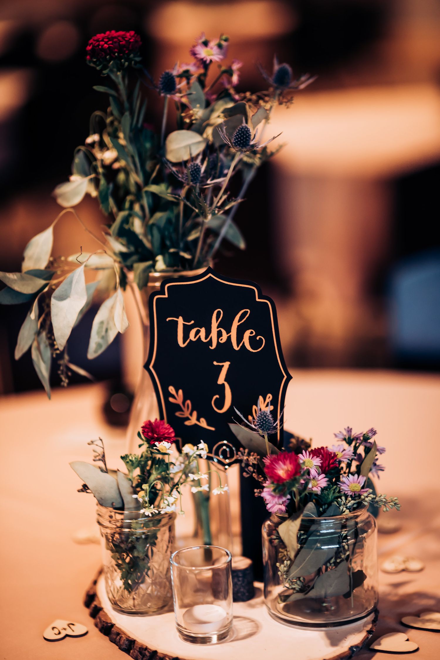 Elegant wedding table centerpiece with Table 3 sign and wildflowers in mason jars.
