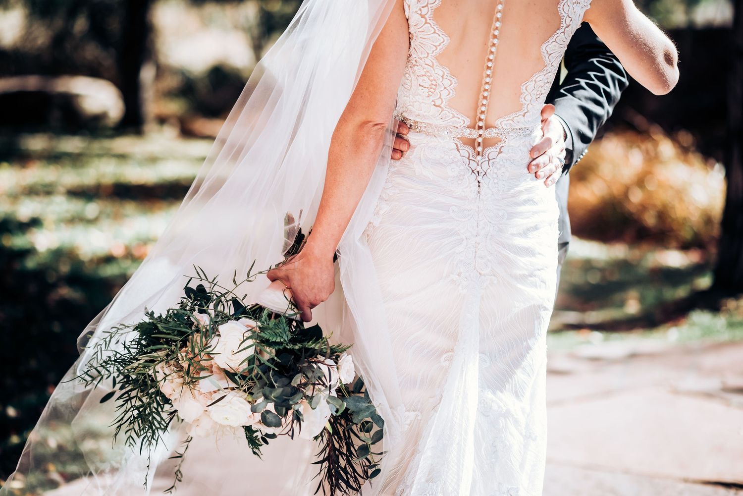 Wedding portrait under stunning red maple trees with sunlight filtering through branches.