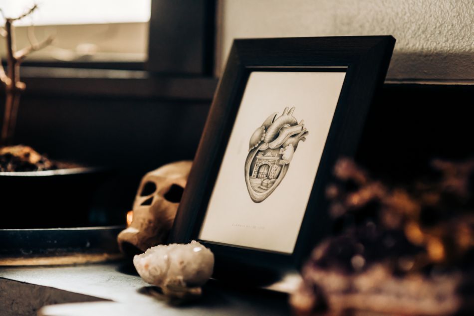 Framed anatomical heart drawing with decorative elements on a dark wooden surface.