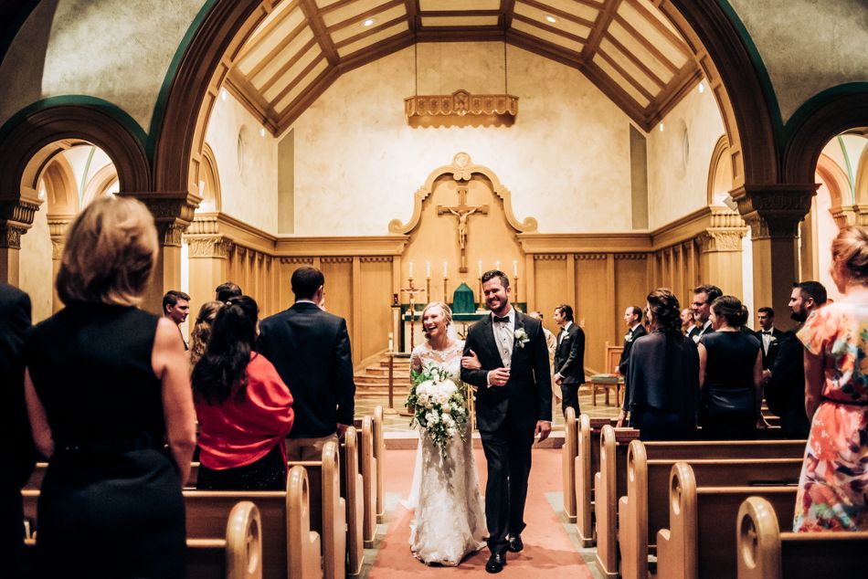 Wedding ceremony in a historic chapel with wooden beams and arched architecture.
