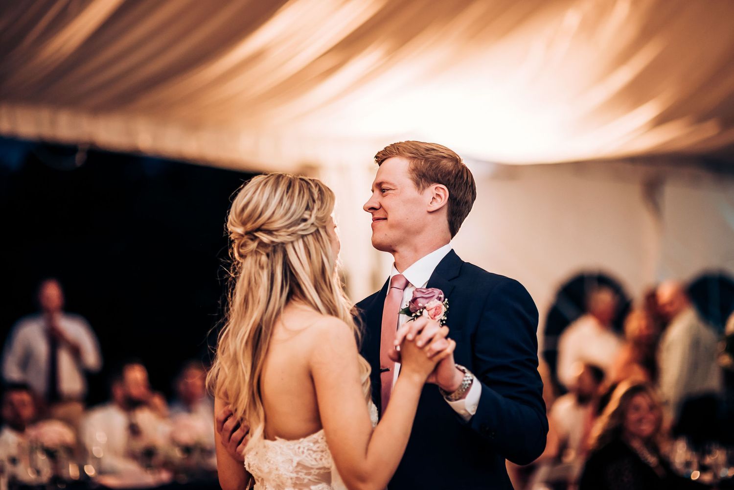 Romantic dance moment captured during wedding reception under warm tent lighting.