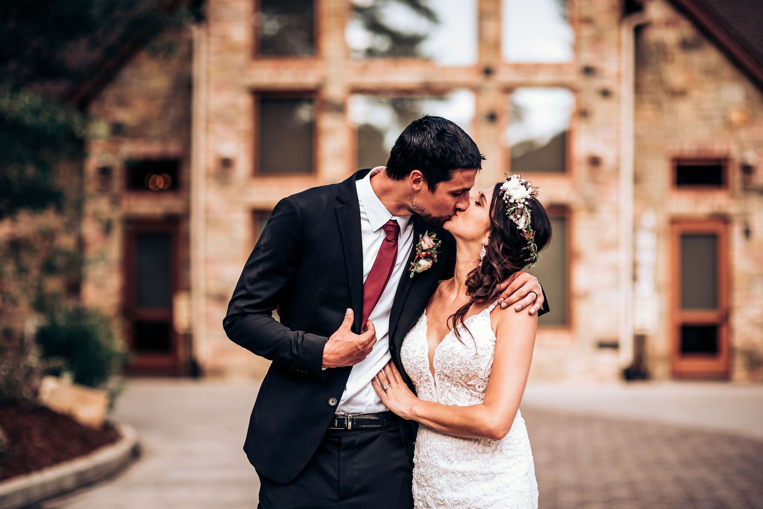 Elegant wedding portrait in front of rustic brick building with classic formal attire.