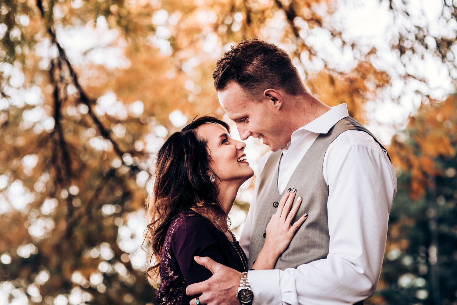 A tender romantic moment between a couple against an autumn backdrop.