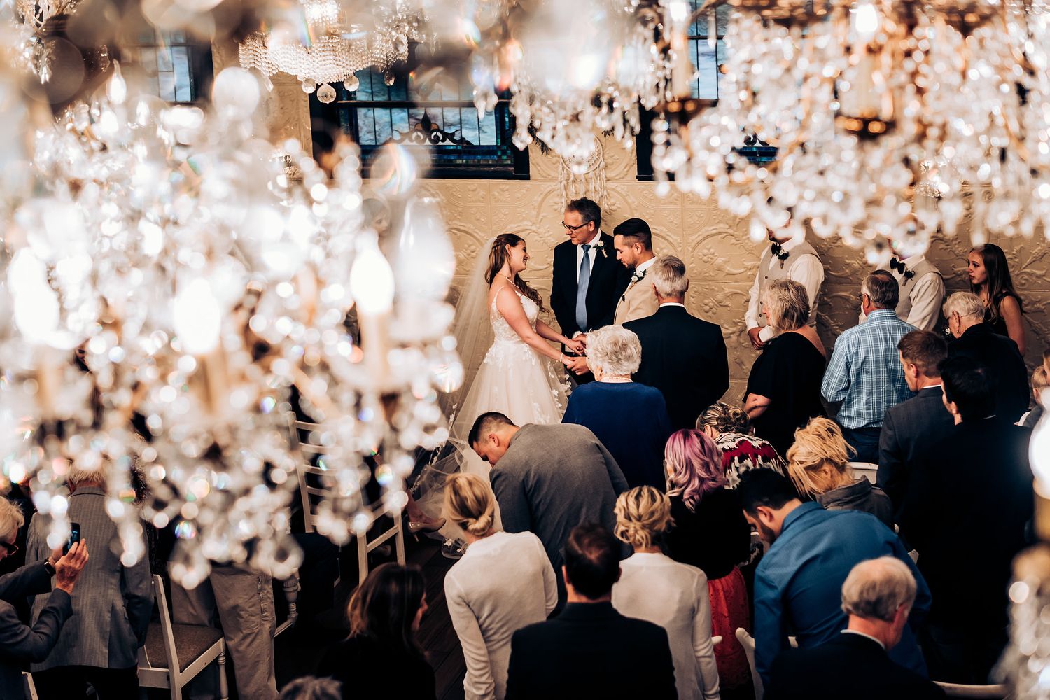 Wedding celebration viewed from above with crystal chandeliers creating a magical atmosphere.
