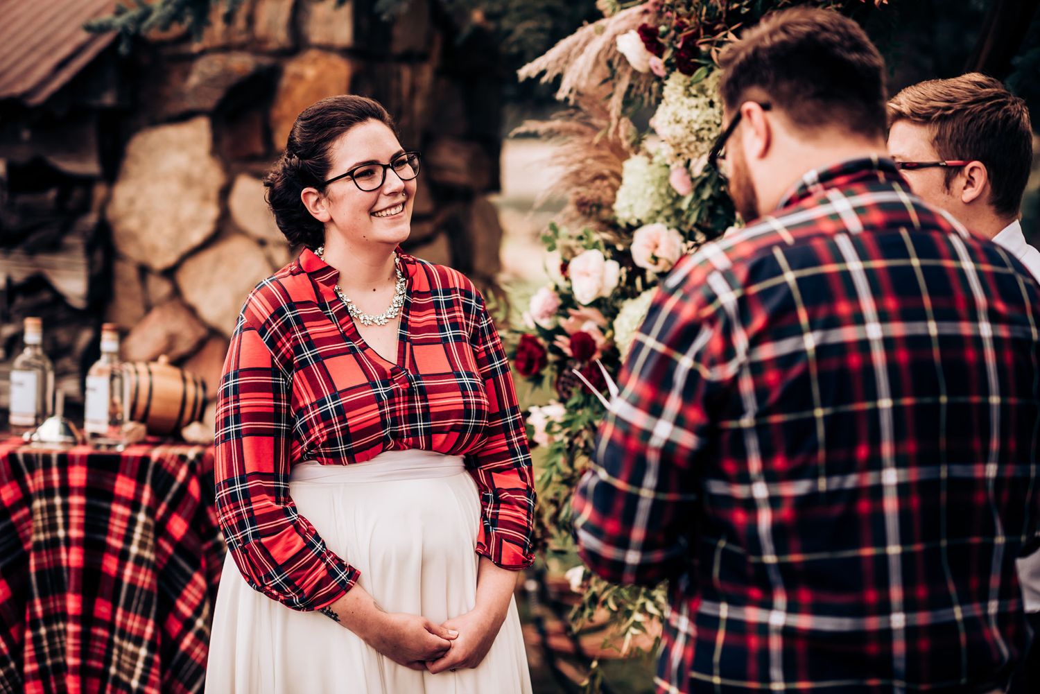 A couple shares a moment during their rustic outdoor wedding ceremony decorated with flowers.