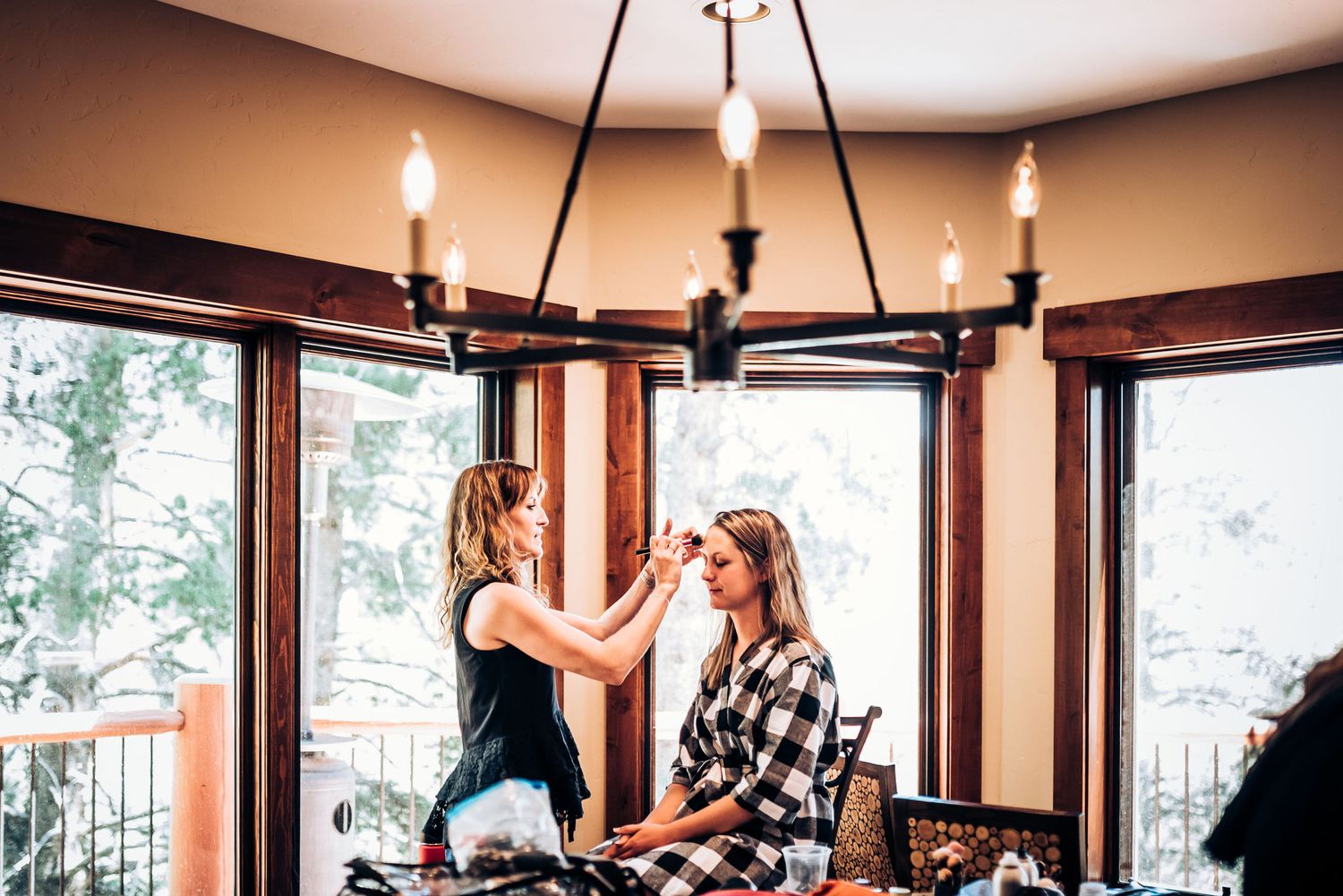 Wedding day preparation scene in rustic wooden room with chandelier lighting.
