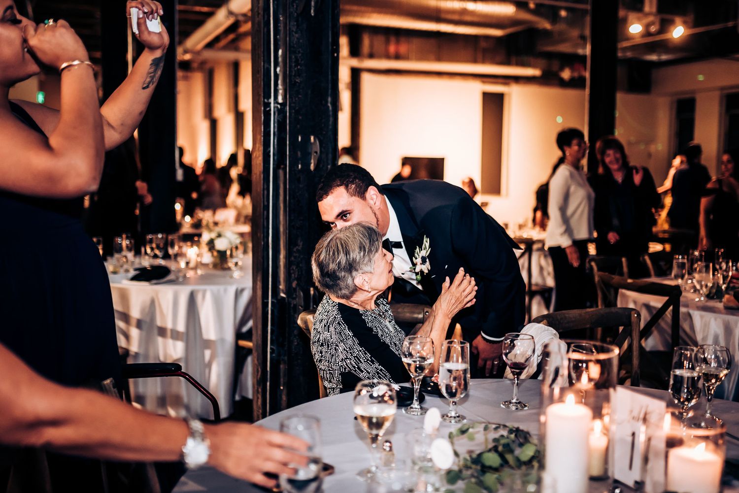 Guests sharing an intimate moment during a candlelit wedding reception dinner.