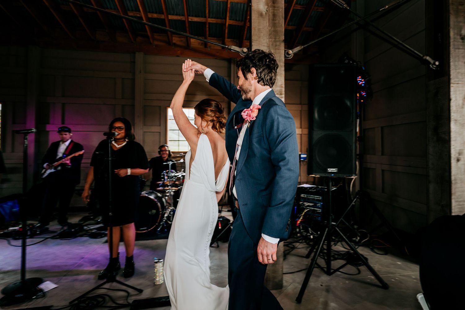 Dancing couple in formal attire at wedding reception with band in background.