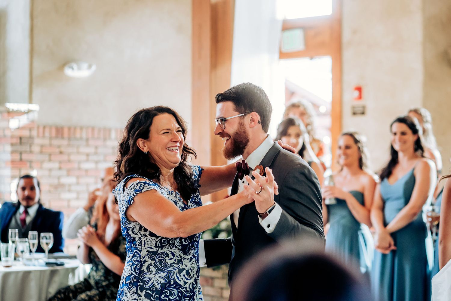 A couple shares an intimate dance moment during a wedding celebration while guests look on.