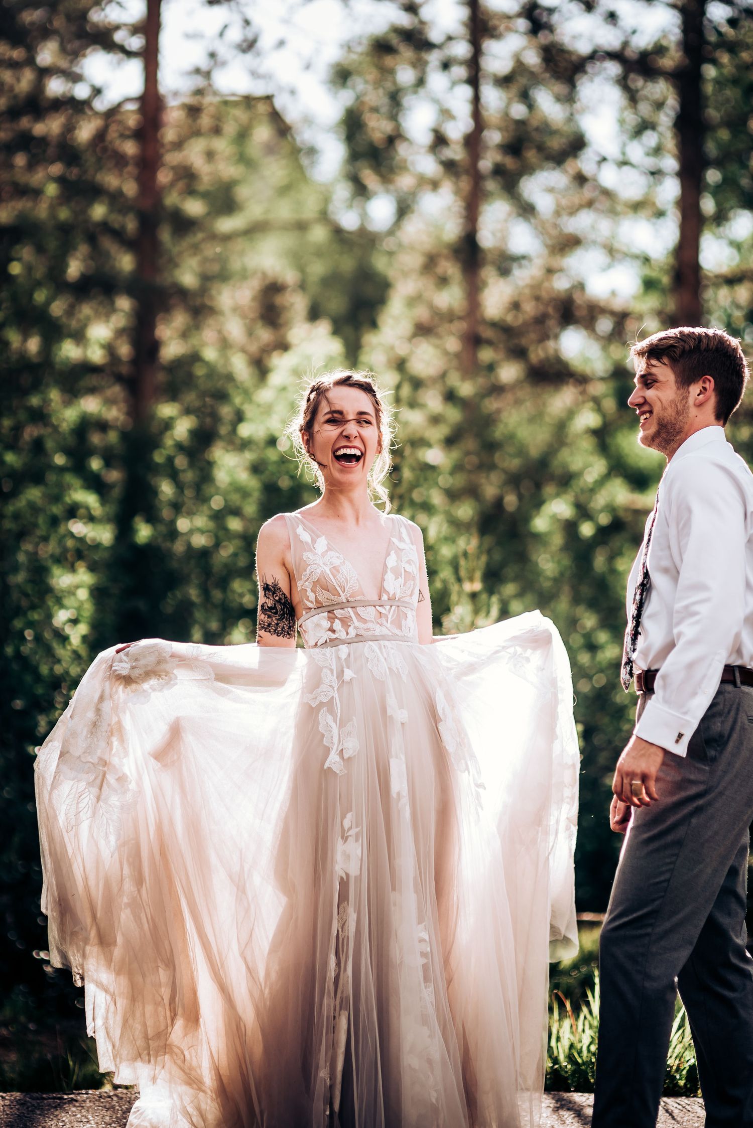 A joyful moment in nature as the bride twirls her flowing champagne-colored dress among pine trees.
