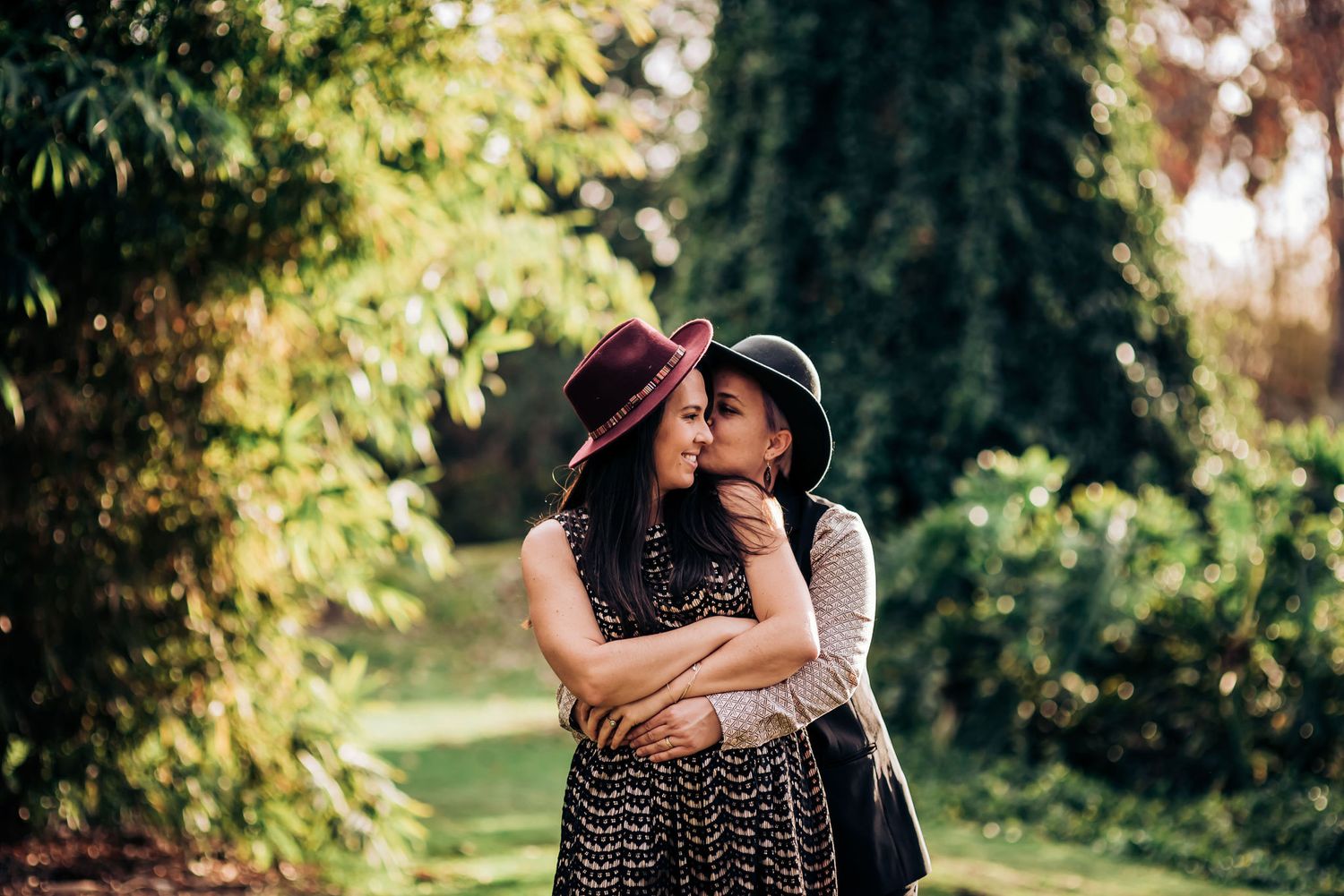 Couple shares an intimate embrace in a sunny garden setting.