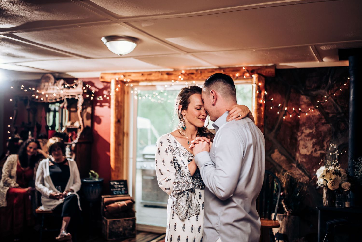 Couple sharing a romantic dance moment under string lights at an indoor celebration.